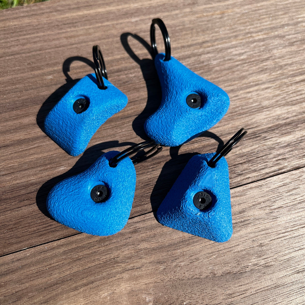 Four blue climbing holds on a wooden surface