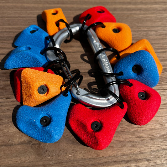 Colorful climbing holds on a metal carabiner against a wooden background