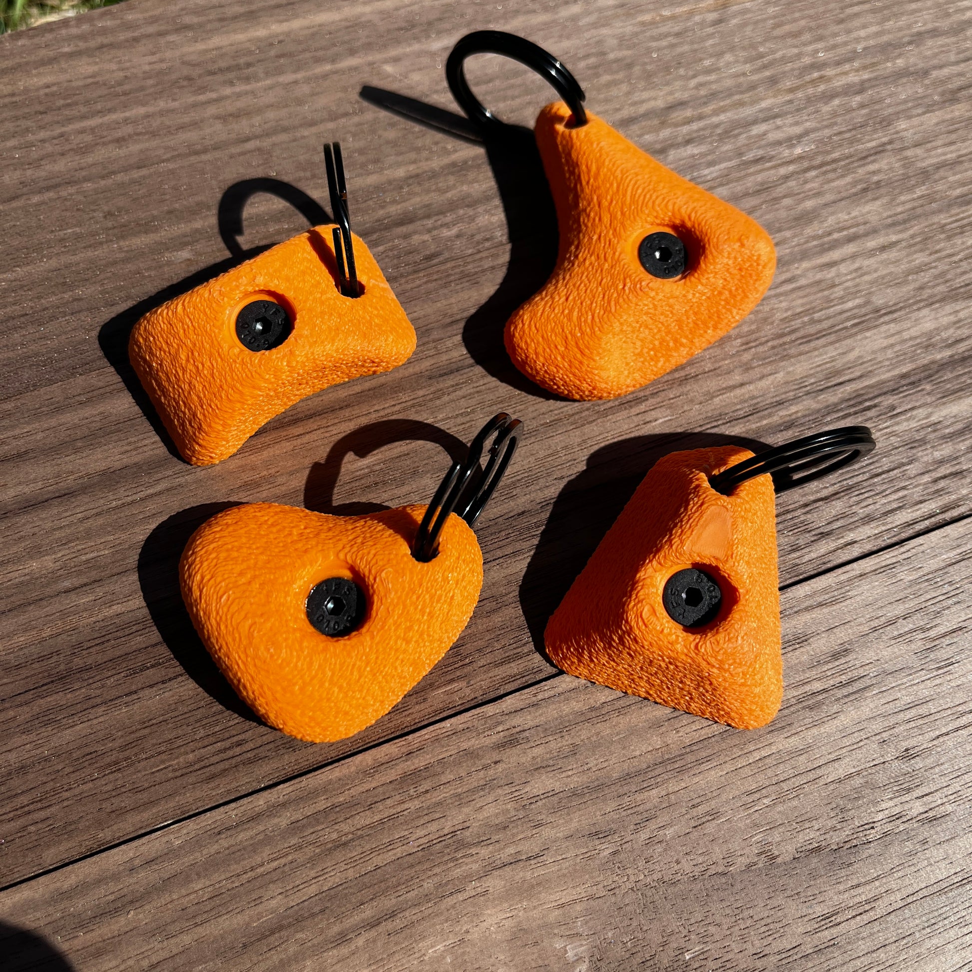 Four orange rock climbing holds on a wooden surface